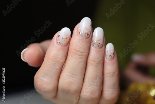 Shimmering gold manicure. A hand displays beautifully manicured gold particles nails adorned with glittering polish. 