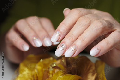 Shimmering gold manicure. A hand displays beautifully manicured gold particles nails adorned with glittering polish. 