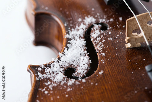 Close up of violin f hole covered in white artificial snow on clean background