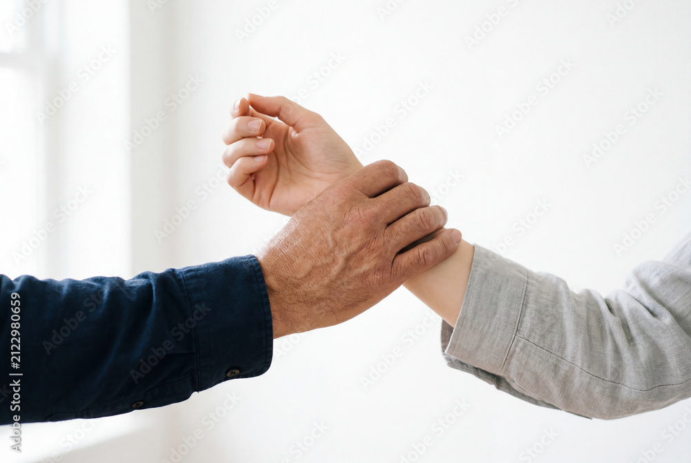 Fototapeta premium Hand firmly grasping the wrist of another person nearby