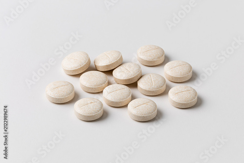 Pills are arranged in a neat row on a plain white surface