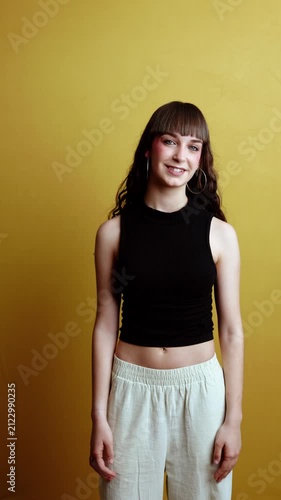 Confident young woman with bangs smiling on a yellow background