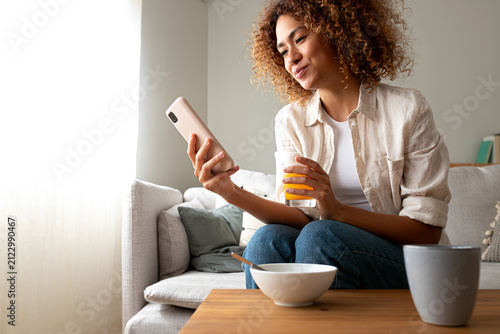 Young woman relaxing on sofa using smartphone