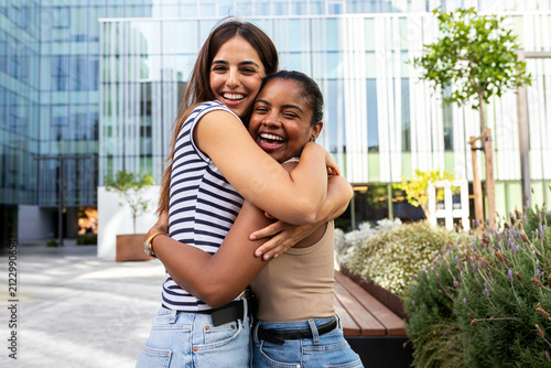 Diverse friends hugging laughing together in urban park