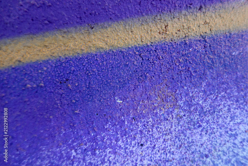 Urban graffiti wall with purple spray paint texture with one yellow line