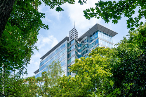 Modern sustainable office building surrounded by lush green trees in Brussels, blending contemporary corporate architecture with urban nature and a peaceful business environment