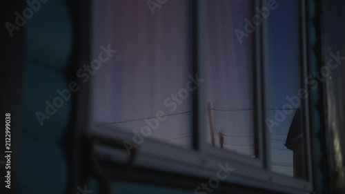 Beautiful evening sky with gradients of pink and blue reflecting in the glass pane of a residential building's window as the light fades, creating a cinematic and moody atmosphere
