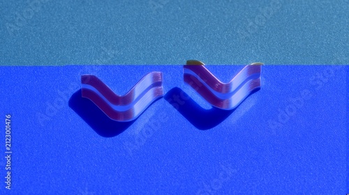 Two metallic chevron shapes with linear accents on a blue textured surface display