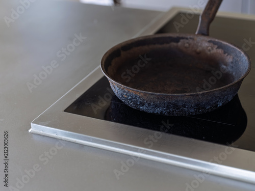 Cuadro en lienzo A cast iron frying pan sits on an induction hob set in a stainless steel kitchen worktop