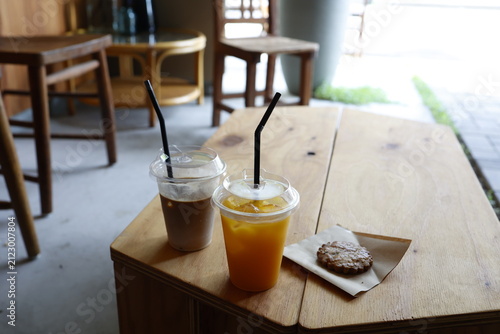 カフェ店内のドリンクとクッキー。オレンジジュースとコーヒー。木製テーブル