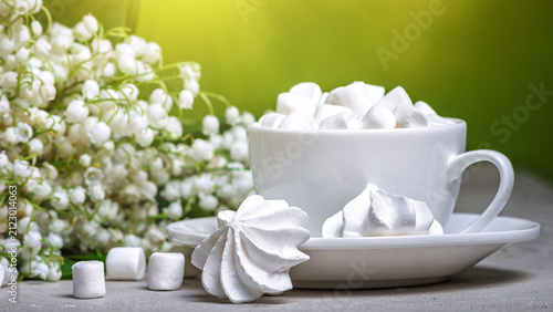 Spring still life - marshmallows on the background of a bouquet of lilies of the valley, closeup