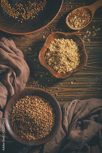 Rural still life with top view of the buckwheat flakes and the peeled groats of buckwheat, on a wooden surface closeup