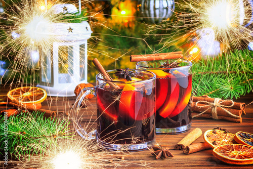 Christmas mulled red wine glühwine with aromatic spices and citrus fruits on a wooden rustic table, close-up. Traditional hot drink or festive cocktail at Christmas or New Year time.