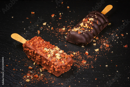 Chocolate cake pops with nuts in form of popsicle on stick on black slate board background