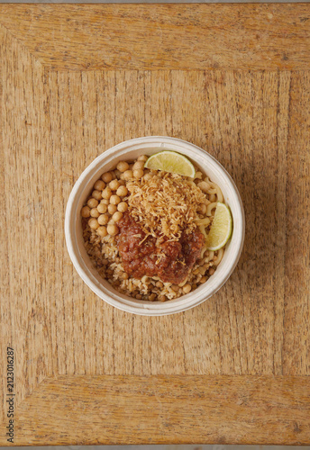Small koshari bowl on rustic wooden background egyptian food vertical moody photography