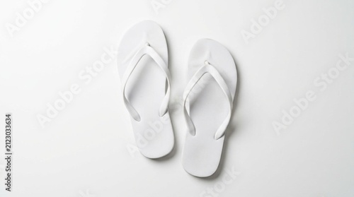 Pair of plain white rubber flip flop sandals arranged casually on clean white surface with soft overhead studio lighting and minimal shadow