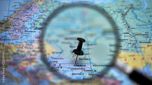 Fotografie Magnifying glass focusing on map with pin near Kharkiv and Zaporizhzhia