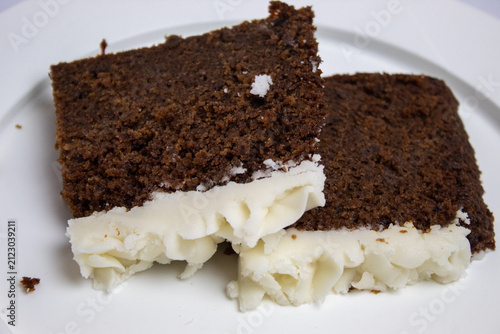 Close-up of two slices of plum cake on a large plate against a white background.