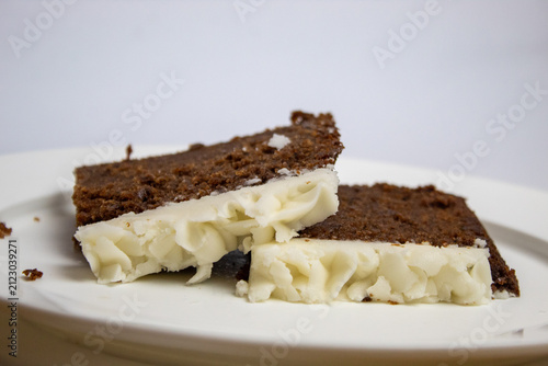 Close-up of two slices of plum cake stacked on top of each other, with white frosting.