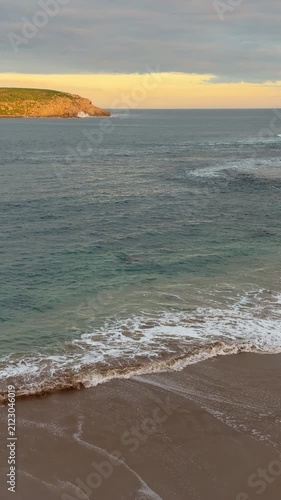 Gentle waves lap at the shore at Kings Beach in South Australia at sunset in 4k vertical footage