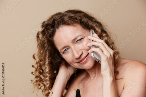 Foto Middle aged woman on the phone with a soft smile, natural skin visible, studio p