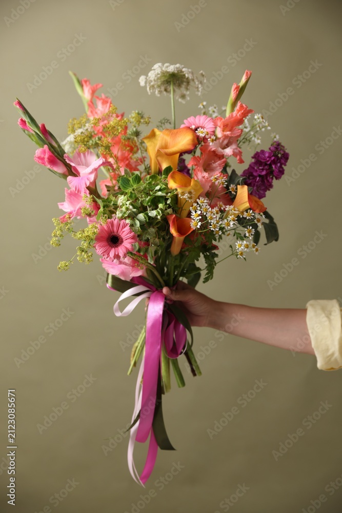 Obraz premium Woman with bouquet of beautiful vibrant flowers on olive background, closeup