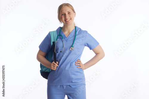 Obraz na płótnie An upbeat young woman in light blue scrubs and a stethoscope poses with her hand on her hip and a backpack, ready to begin her journey in healthcare and nursing education