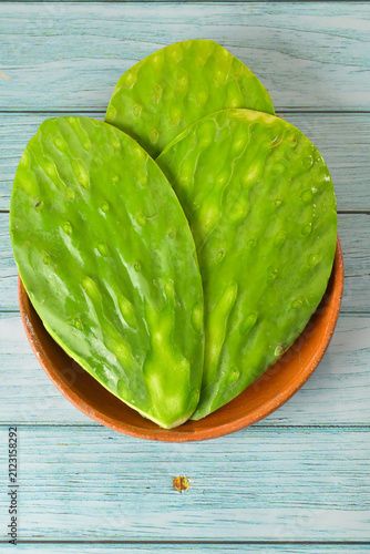 Fresh tender nopales in a clay plate placed on a rustic wooden background