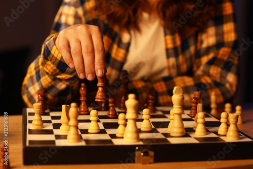 Foto Person in a plaid shirt making a strategic move with a dark chess piece on a che