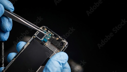 Closeup of a technician repairing a smartphone internal circuit board