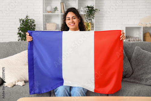 Beautiful young happy African-American woman with flag of France sitting on s...