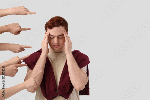фотографія People pointing at stressed young man on white background