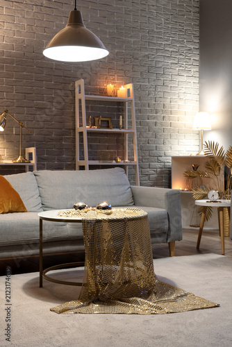 Interior of stylish living room with golden decor, glowing lamps and sofa at ...
