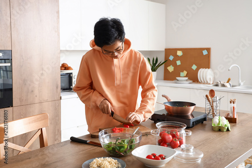 Young Asian man cutting tom...