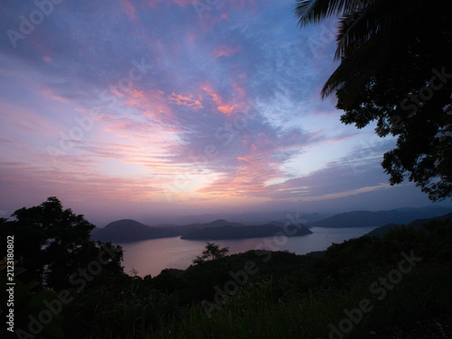 Scenic landscape of calm lake and mountains under colorful sky at dawn