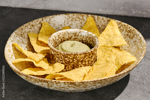 Foto Crispy corn nachos surround velvety guacamole in a rustic bowl for a Mexican par