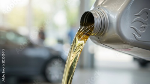 Close up of motor oil pouring from jug into engine