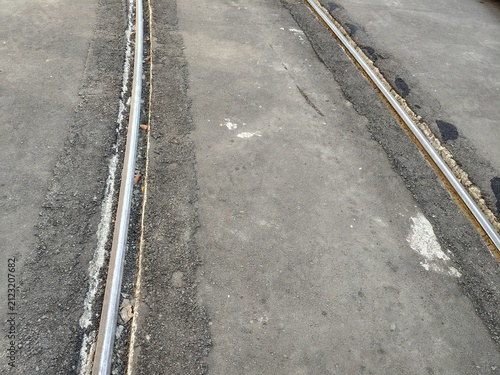 Obraz na płótnie Steel tram rails embedded in gray asphalt road surface in urban city transportat