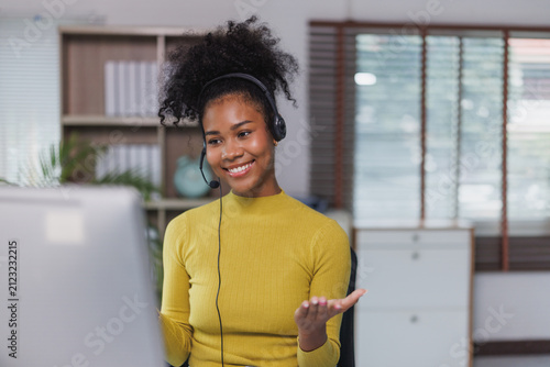 Woman working customer support headset smiling at computer
