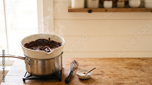 Chocolate melting in double boiler on wooden table in kitchen  