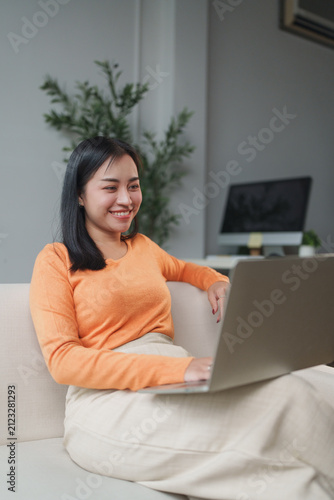 Young woman smiling, working from home on laptop