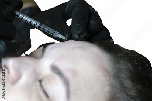woman lies in an armchair, receiving a cosmetic injection, a close-up of a rejuvenating injection in the forehead,