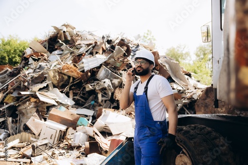 Fotografie Worker talking on phone at metal scrapyard