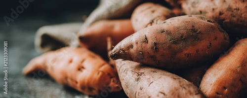 Ultra wide macro shot of sweet potatoes with rough orange-brown skin. Soft lighting highlights surface texture and natural variation in premium food photography.