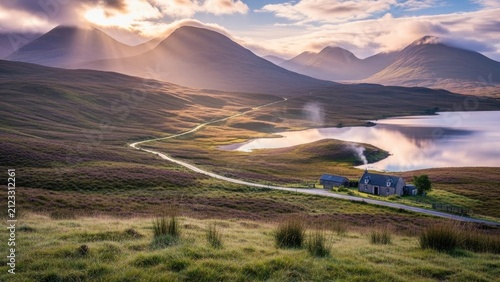 Highland valley at dawn with sunbeams over mountains and winding road