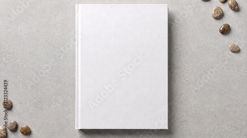 Blank white hardcover book mockup on a textured grey surface with small stones