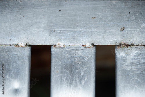 Close up of weathered metal drain grate with scratches and weld joints.A detailed close-up shot of a stainless steel or iron drainage grate texture. 