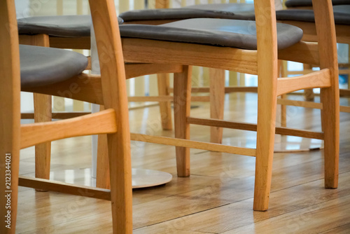 Close-up view of wooden chairs with dark upholstered seats arranged in a row