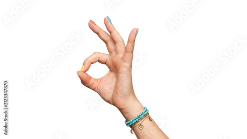 Woman’s hand making an OK sign with yellow manicure, turquoise bracelets and charm jewelry, isolated on a transparent background