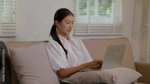 Woman using laptop on couch in warm cozy living room